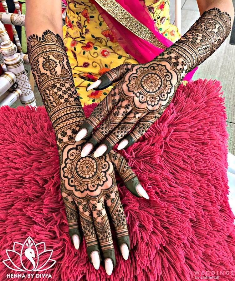 Photo of mandala backhand mehendi design, surrounded by traditional attire.