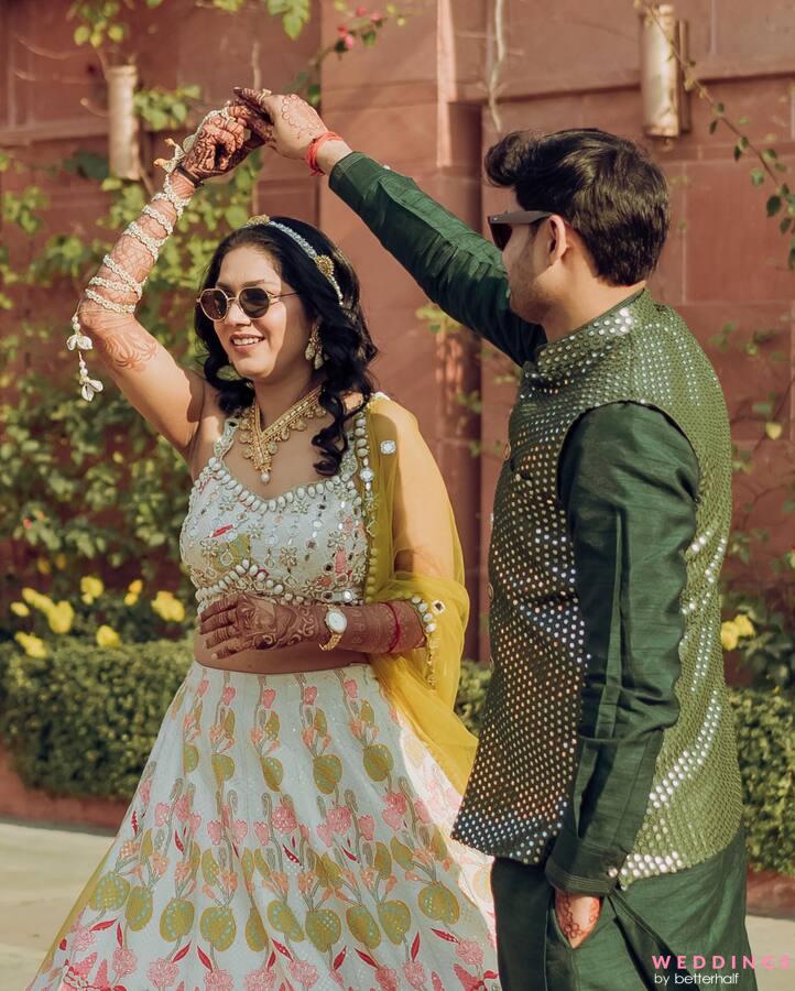 Photo of A bride in green lehenga twirling while the groom looks on
