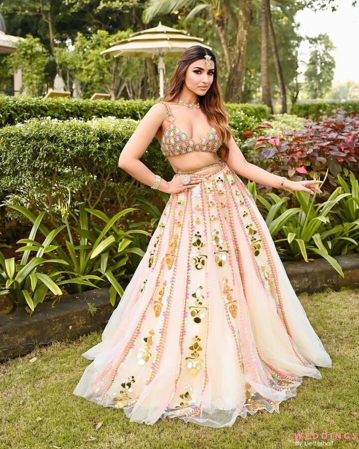 Discover designer peach bridal lehengas with intricate floral embroidery. Strike a pose in the garden with a vibrant umbrella.