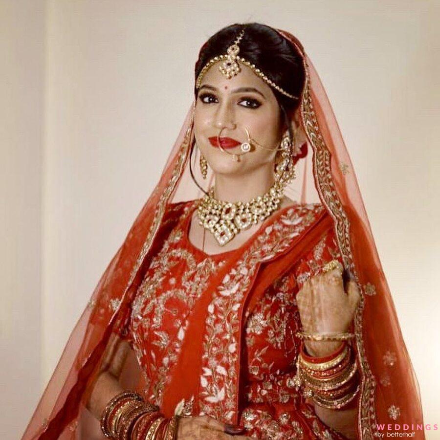 Photo of A bride in orange lehenga and gold jewellery at her Anand Karaj