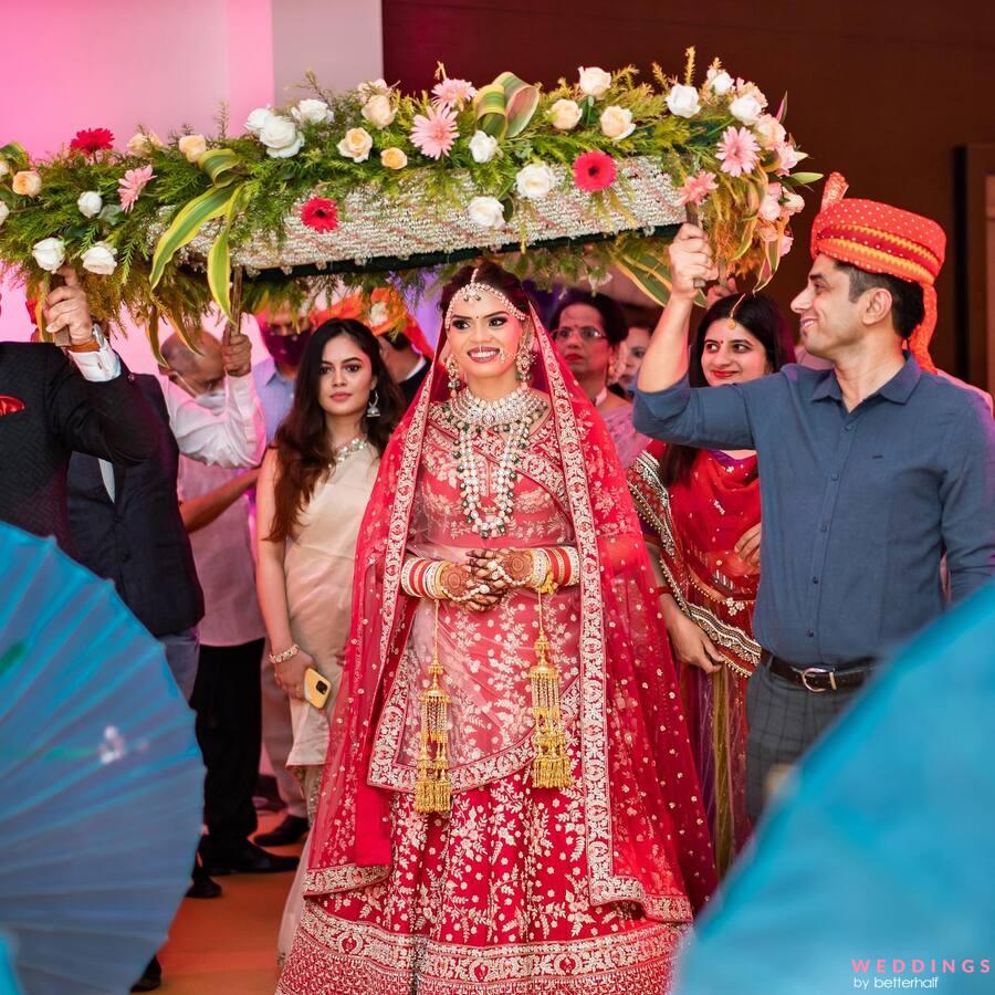 Photo of bride and groom in contrasting outfits with grey sherwani and red  lehenga